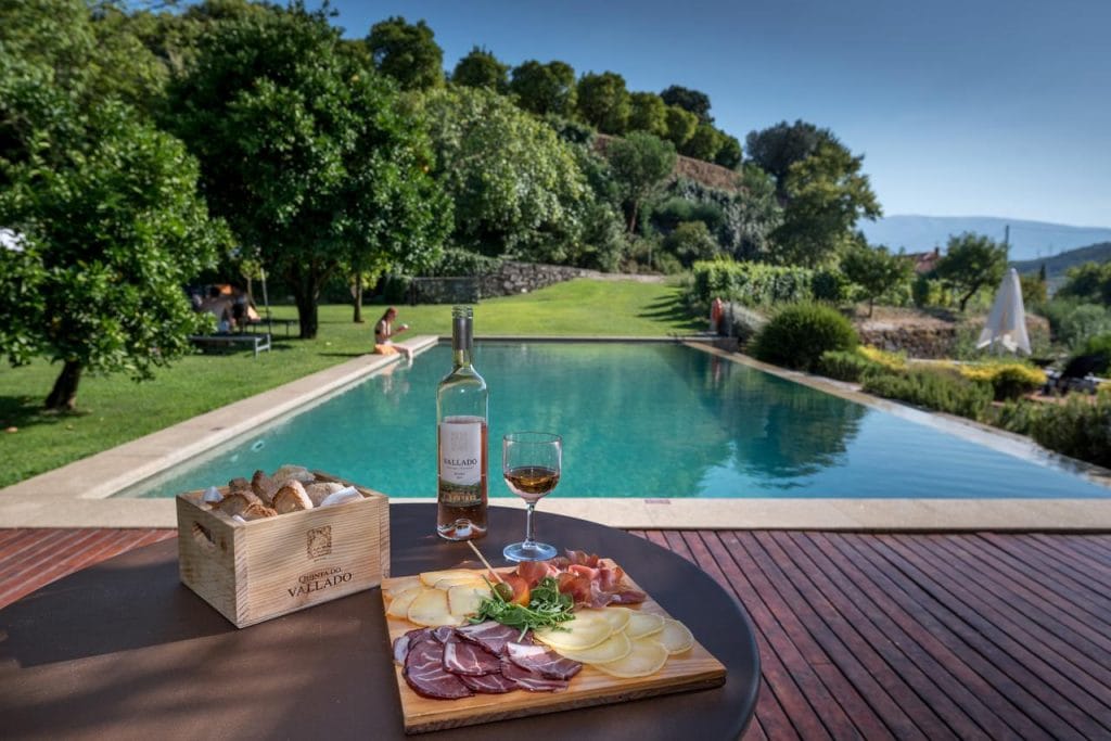 the backyard pool with local snacks on a table surrounded by nature in the Quinta do Vallado Wine Hotel in Portugal