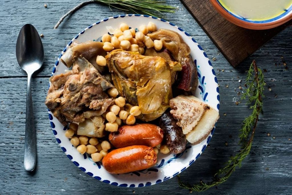 cocido madrileno com grão-de-bico e diferentes carnes em um prato tradicional espanhol