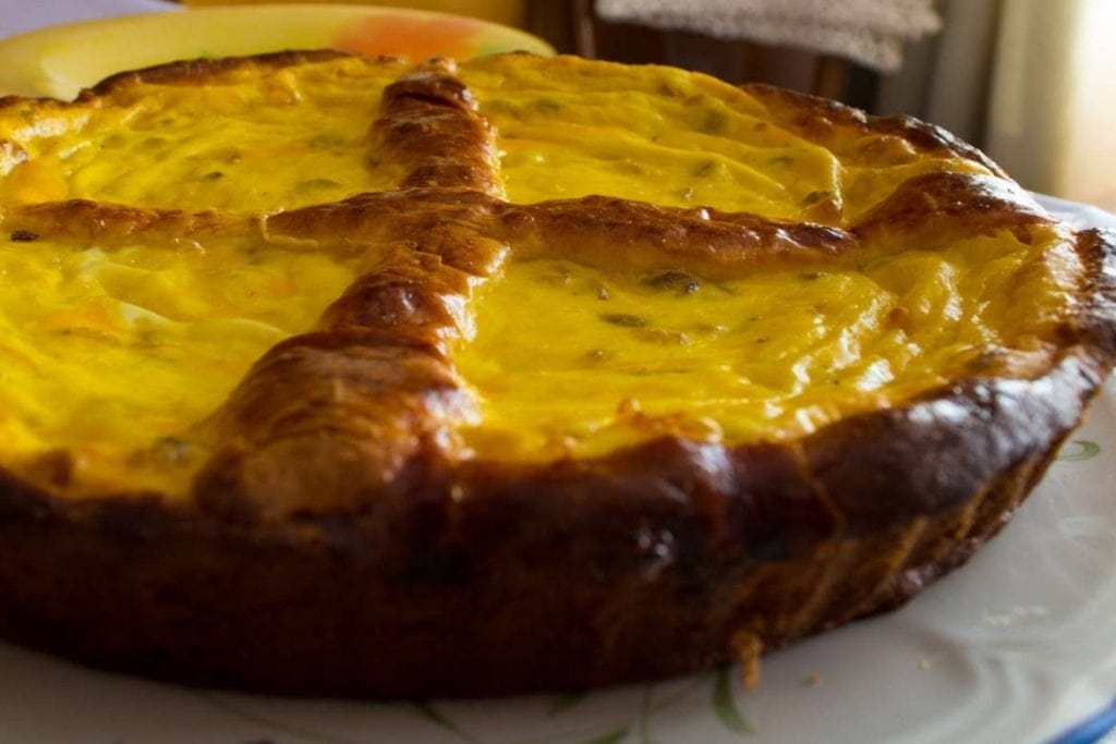 Pão doce romeno feito com queijo e passas, de formato redondo e cor dourada em cima típico pão de Páscoa