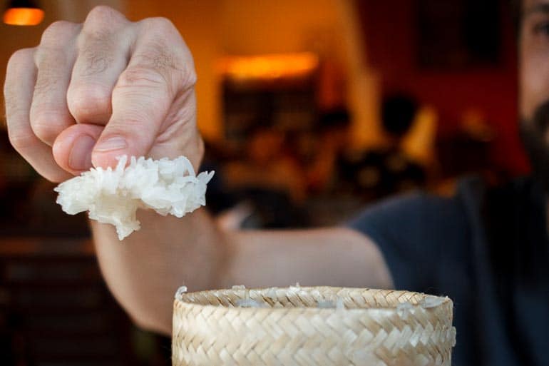 Porção de arroz glutinoso preso no dedo