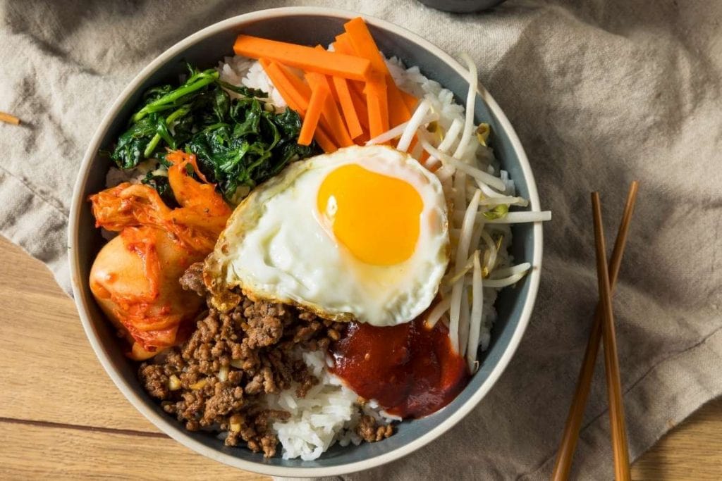 a bowl with bibimbap a famous korean rice dish with vegetables, egg, rice and other ingredients