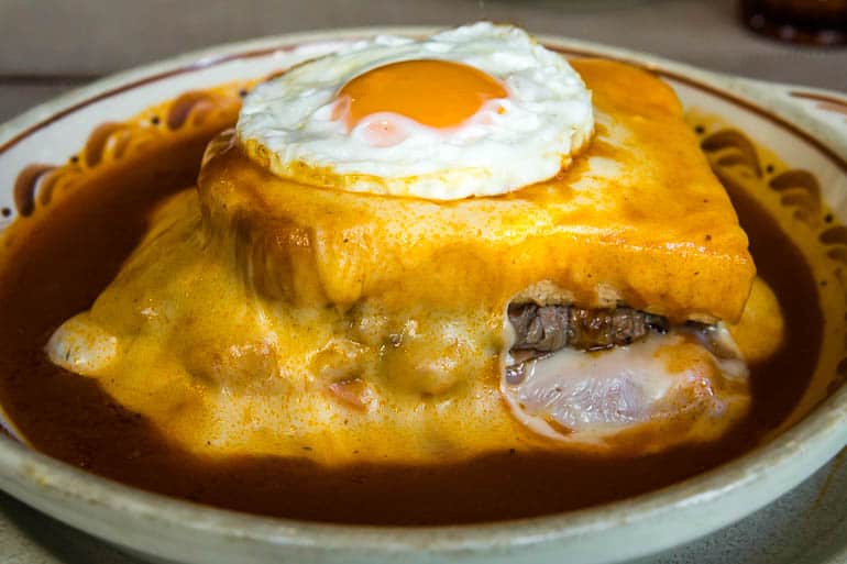 a tradicional francesinha de porto com muito queijo e um ovo estalado por cima