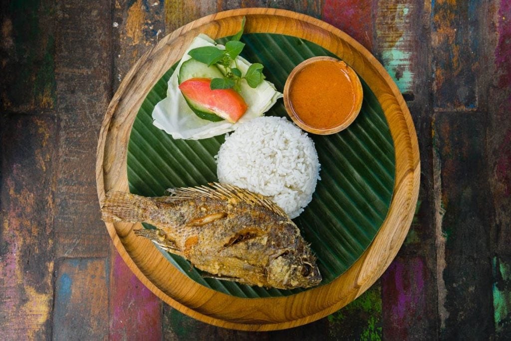 banana leaf plate with deep fried fish, rice and sambal sauce traditional dish in Indonesia