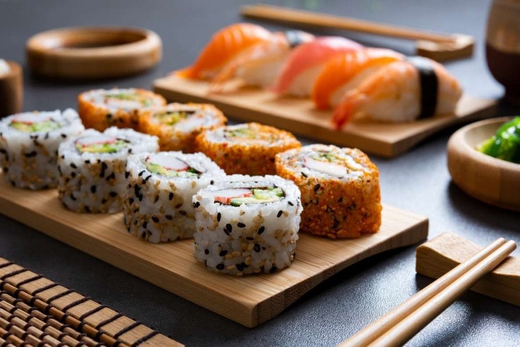 diferentes tipos de sushi japonês com arroz em uma tábua de madeira