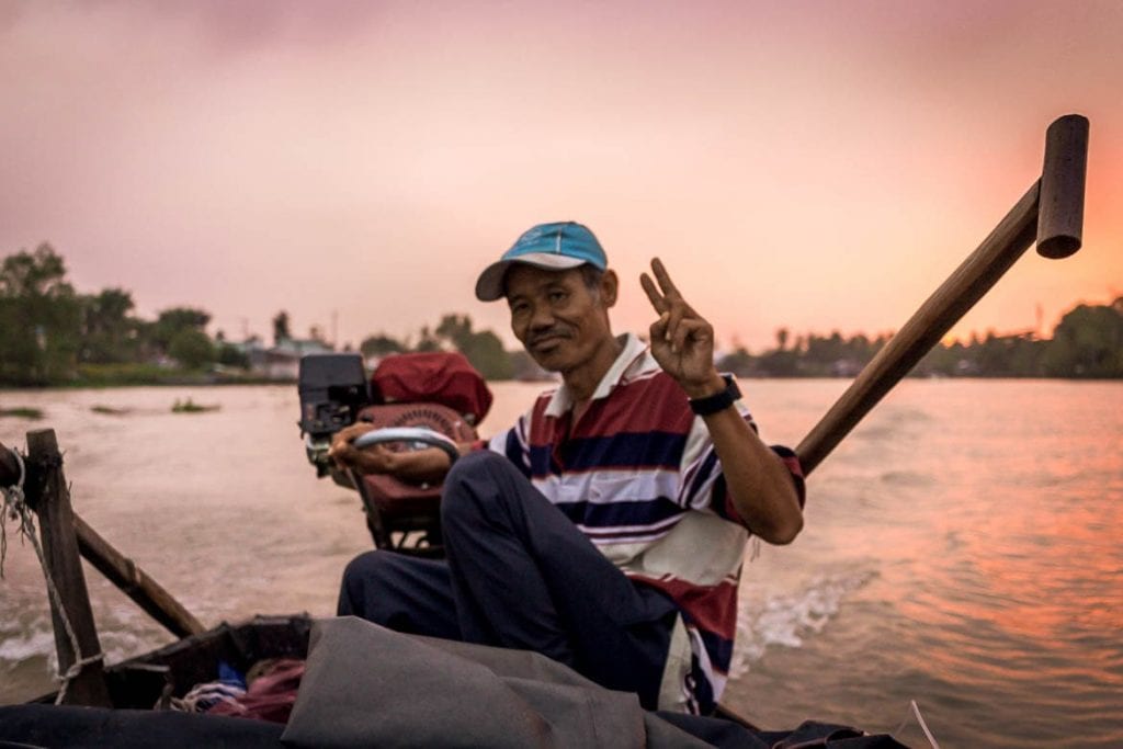 anfitrião local dirigindo um barco no rio Mekong durante um turismo de base comunitário no Vietnã