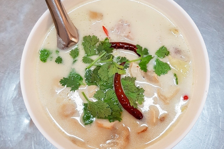 Uma tigela com Tom Kha Gai, uma sopa tailandesa de frango com leite de coco