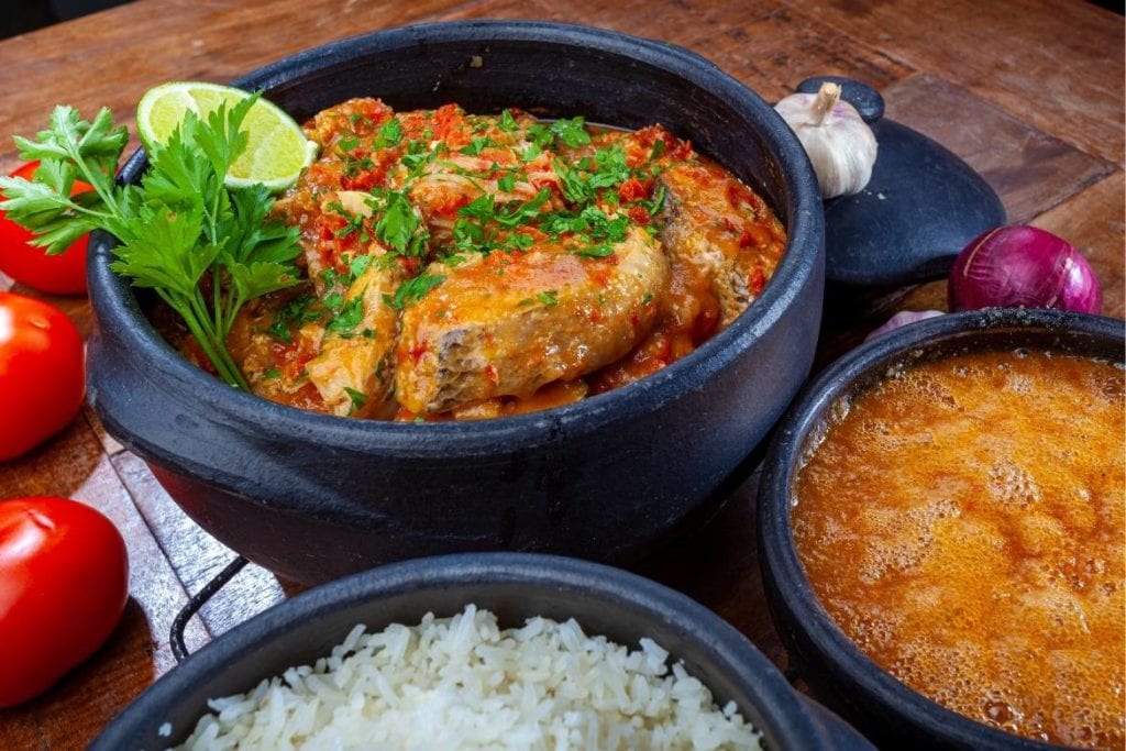 moqueca capixaba served in claypot with side bowls of pirão (fish gravy) and white rice